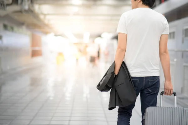 Asijský mladík držení oblek a zavazadel v terminálu letiště — Stock fotografie