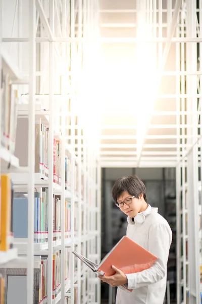 Young Asian man university student reading book in library