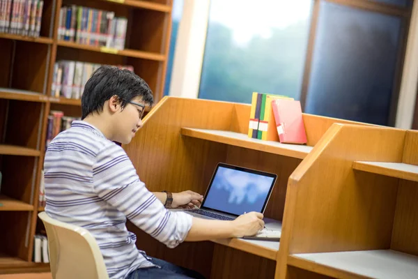 Jeune étudiant asiatique à l'université utilisant un ordinateur portable dans la bibliothèque — Photo