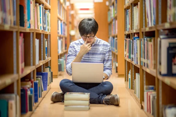 Jeune étudiant asiatique à l'université utilisant un ordinateur portable dans la bibliothèque — Photo