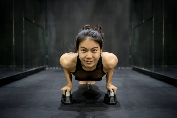 Молодая азиатская спортсменка делает отжимания на полу — стоковое фото
