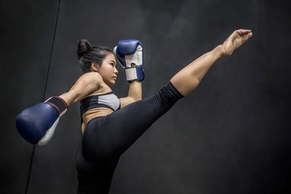 Jovem mulher asiática boxer com luvas de boxe chutando — Fotografia de Stock