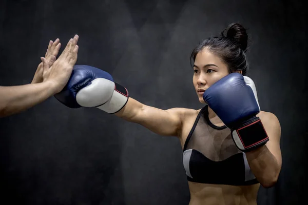 Young Asian woman boxer punching to her trainer