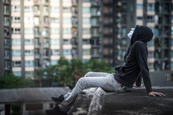 Mistero uomo in maschera bianca seduto sul tetto di edifici abbandonati — Foto Stock