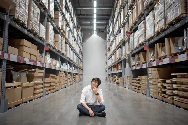 Joven asiático hombre sentado en almacén elegir qué comprar — Foto de Stock