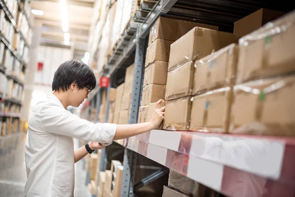 Junger asiatischer Mann wählt Produkt im Lager — Stockfoto