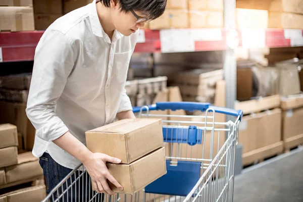 Küçük Asya adam koyarak kağıt kutular içine warehou arabası sepeti