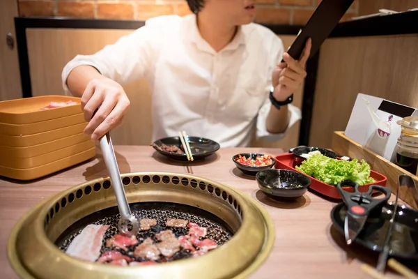 Jonge Aziatische man eten Koreaanse Barbecue buffet in het restaurant — Stockfoto