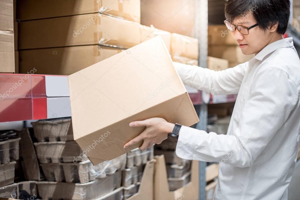 Young Asian man carrying paper boxes in warehouse