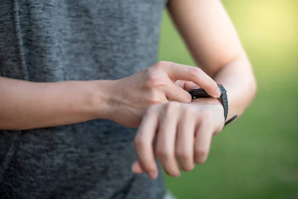 Male hand pressing button menu on smart watch after running