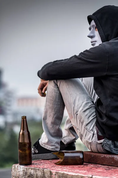 Mistério homem na máscara sentado com garrafa vazia e quebrada — Fotografia de Stock