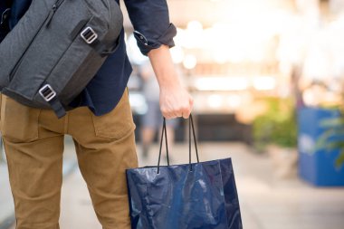 Mağazada mavi alışveriş çantası tutan erkek el