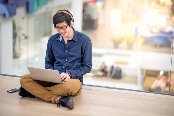 Fiatal ázsiai üzletember hallgató-hoz zene rövid idő használ a laptop — Stock Fotó