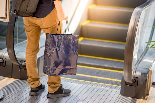Mão masculina segurando saco de compras azul na loja de departamento — Fotografia de Stock