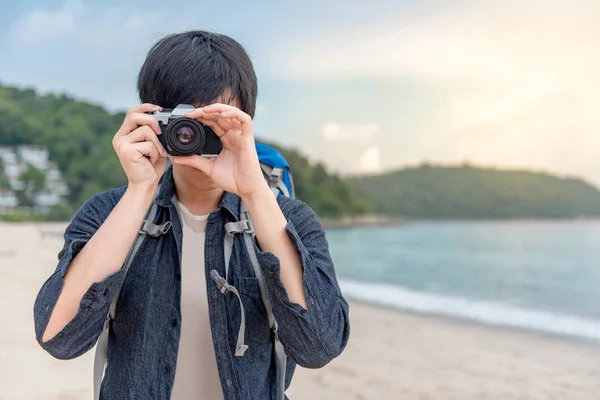 Fiatal ázsiai férfi fotós figyelembe fotó a strandon — Stock Fotó
