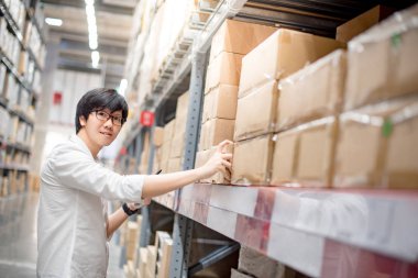 Genç Asyalı adam depoda ürün seçimi