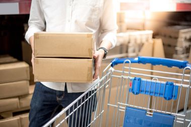 Genç adam arabası sepeti depoda kağıt kutuları koyarak