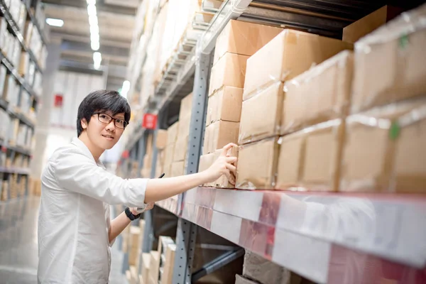 Joven asiático hombre elegir producto en almacén —  Fotos de Stock
