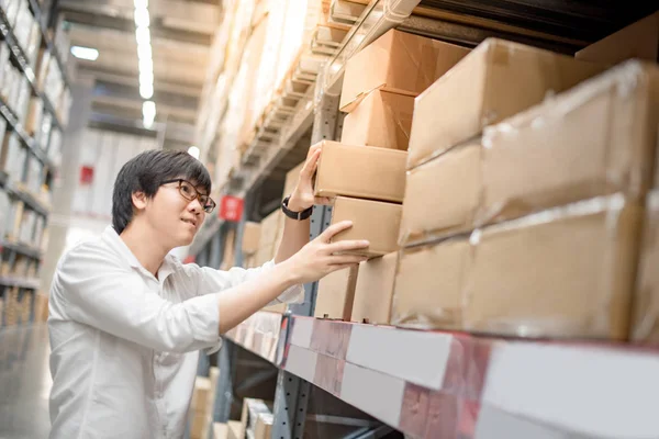 Joven asiático hombre recogiendo cajas de papel en almacén — Foto de Stock