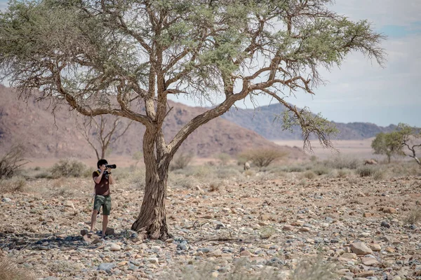 Un tânăr fotograf face fotografii sub arborele Savanna — Fotografie, imagine de stoc