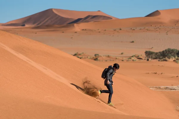 Tânăr asiatic alergând în jos pe dune de nisip în deșert — Fotografie, imagine de stoc