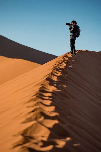 Молодой фотограф стоит на песчаной дюне — стоковое фото