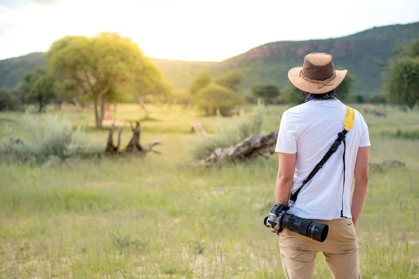 Młody człowiek podróżnik stojąc w safari ogląda dzikich zwierząt — Zdjęcie stockowe