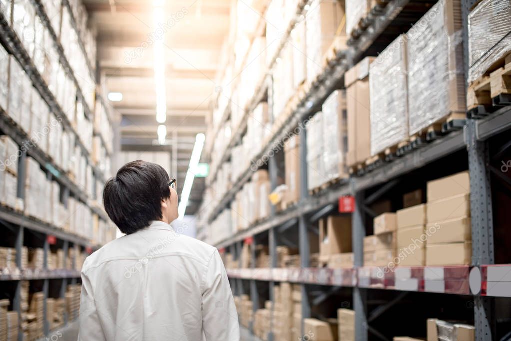 Young Asian man standing in warehouse choosing what to buy