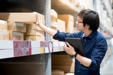 Depoda tablet kullanarak stocktaking yapan genç Asyalı erkek
