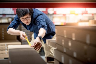 Mezura ile karton kutu kullanan genç Asyalı adam