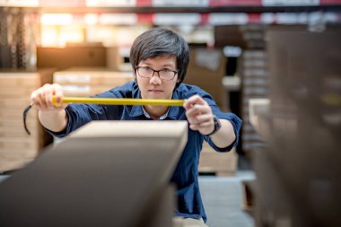 Mezura ile karton kutu kullanan genç Asyalı adam