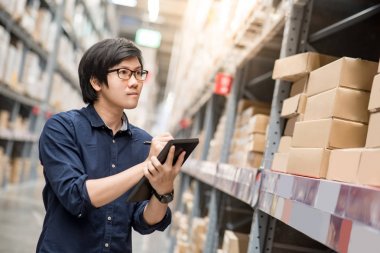 Depoda tablet kullanarak stocktaking yapan genç Asyalı erkek