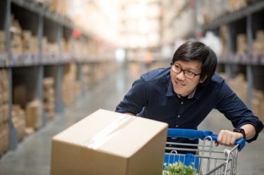 Genç Asyalı adam ambarındaki tramvay arabası ile alışveriş