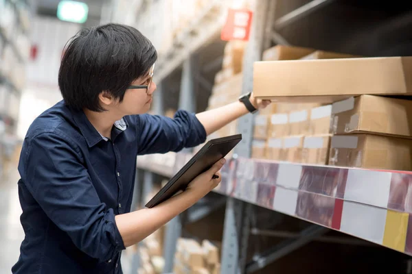 Joven hombre asiático haciendo inventario mediante el uso de tabletas en el almacén —  Fotos de Stock