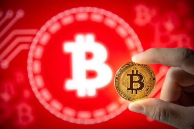 Erkek el bitcoin altın sikke kırmızı grafik arka plan üzerinde gösterilen. Kadar yakın ve bitcoin üzerinde odaklanmak. Dünya çapında cryptocurrency ve dijital ödeme kavramları