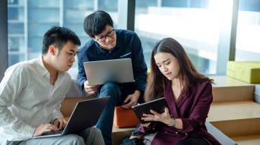 İş yerinde fikir alışverişinde bulunan Asyalı meslektaşlar