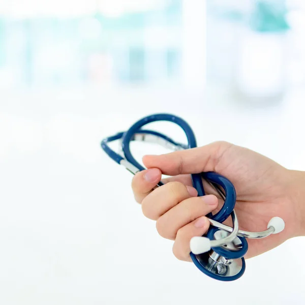 Doctor hand holding blue stethoscope in hospital