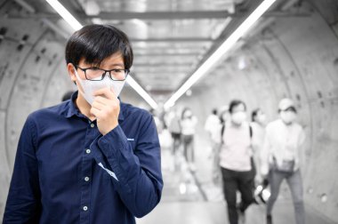Metro tünelinde öksüren maskeli bir Asyalı.