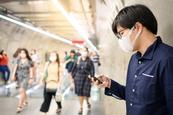 Aziatische man dragen masker met behulp van telefoon in metro — Stockfoto