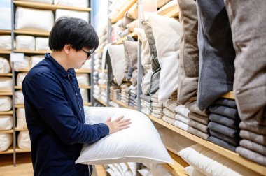 Asyalı adam mobilya mağazasında yastık fırlatmayı seçti