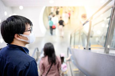 Metro istasyonunda ameliyat maskesi takan Asyalı bir adam.