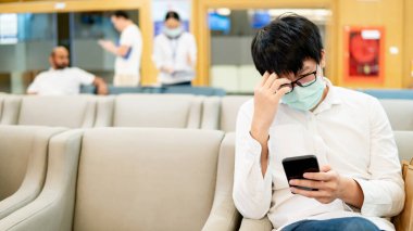 Male patient using smartphone in hospital