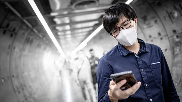 Aziatische man dragen masker met behulp van telefoon in metro — Stockfoto