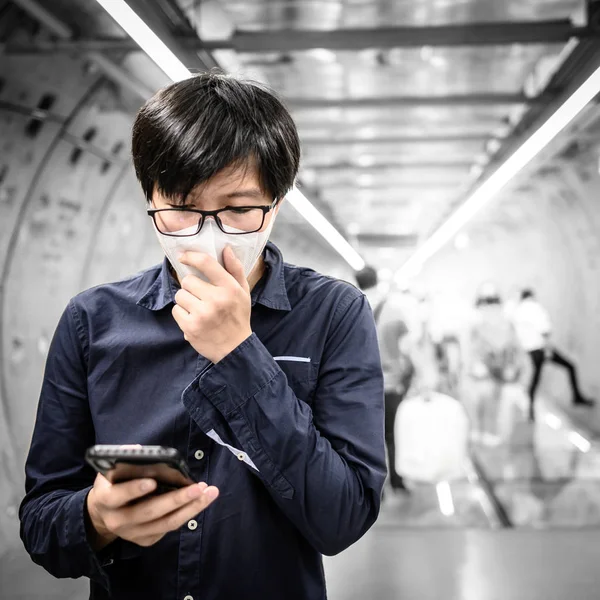 Bărbat asiatic purtând mască folosind telefonul în metrou — Fotografie, imagine de stoc