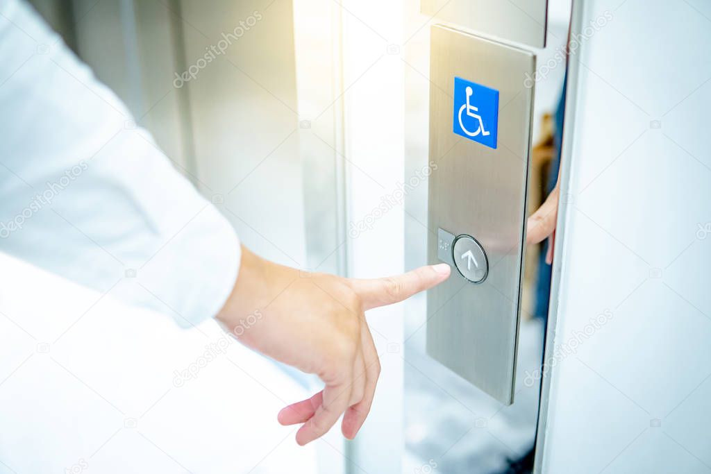 Male hand pressing on up button of disabled lift