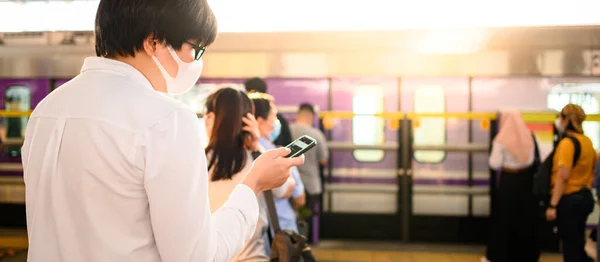 ชายชาวเอเช ยสวมหน ากากผ ดโดยใช สมาร ทโฟนท นวางสถาน Skytrain โคโรนาไวร สหว — ภาพถ่ายสต็อก