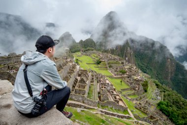 Genç Asyalı gezgin ve fotoğrafçı, Peru 'nun Cusco bölgesindeki yedi harikadan biri olan Machu Picchu' ya bakıyor. Bu görkemli yer 