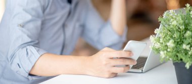 Asyalı işadamı akıllı telefon ve dizüstü bilgisayar kullanıyor. Erkek ofis çalışanı sosyal medya ve internet haberleri için mobil uygulama kullanıyor. İş stratejisi teknolojisi