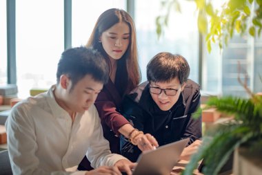 İş toplantısı ve takım çalışması konsepti. İş yerinde dizüstü bilgisayar ve dijital tablet kullanarak proje veri raporunu tartışan Asyalı meslektaşlar. İş arkadaşları ofiste üretken fikirleri paylaşıyor.