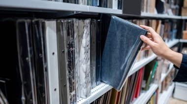 Kırtasiyedeki raftan mavi kumaş desenli yeni klasör klasörü seçen erkek el. Ofis malzemeleri konsepti satın almak